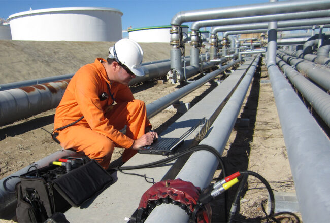 Workers performing maintenance or inspection on a large industrial pipeline. (guided-ultrasonics.com)